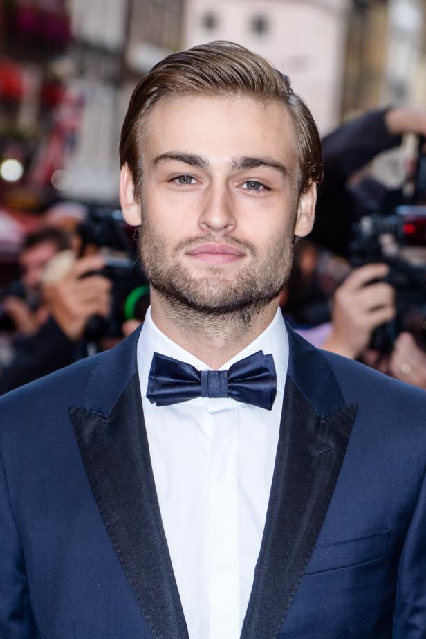 Douglas Booth trägt einen marineblauen Anzug mit Fliege auf dem roten Teppich.