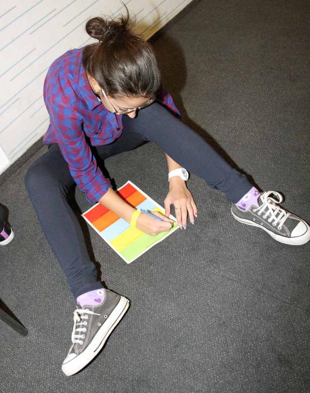 Eine Frau sitzt auf dem Boden und malt ein farbenfrohes Bild.