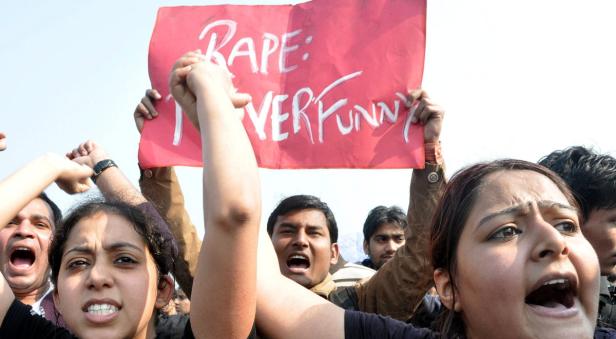 Eine Gruppe von Demonstranten hält ein Schild mit der Aufschrift „Rape: Never Funny“.