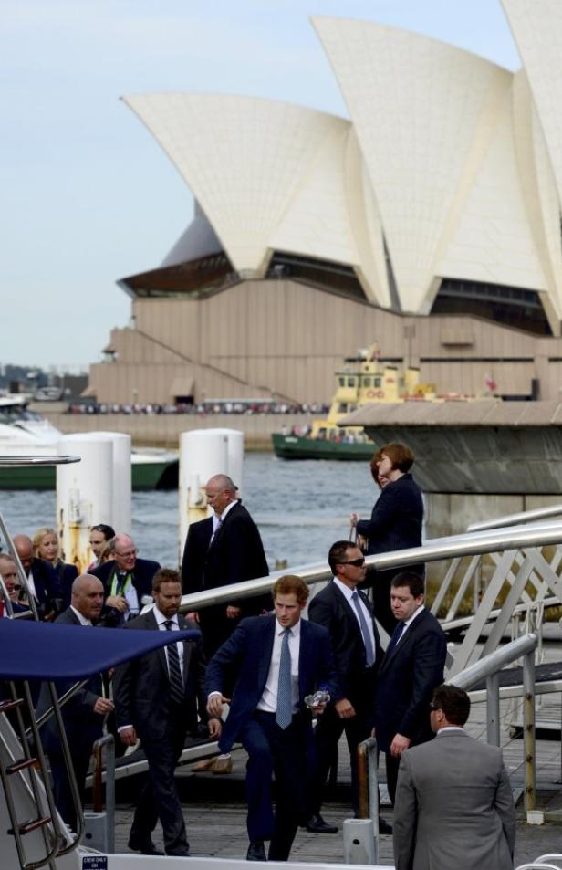 Prinz Harry geht in Sydney mit Sicherheitsleuten im Hintergrund die Treppe hinunter.