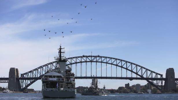 Mehrere Hubschrauber fliegen über die Sydney Harbour Bridge und Kriegsschiffe.