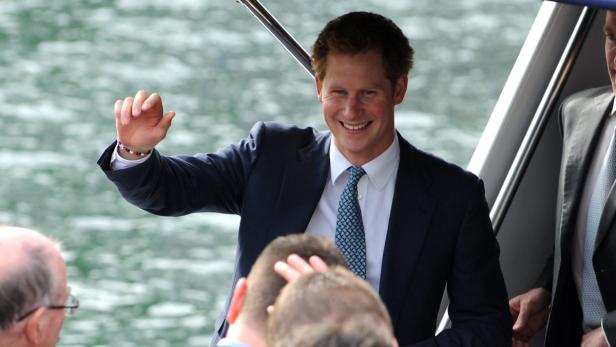 Prinz Harry winkt lächelnd von einem Boot aus.
