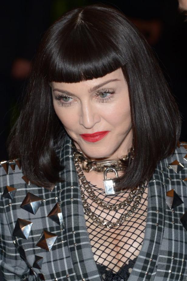 Madonna mit dunklen Haaren, rotem Lippenstift und einer Halskette mit Vorhängeschloss.