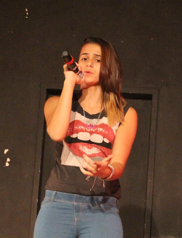 Eine junge Frau singt mit einem Mikrofon in der Hand.