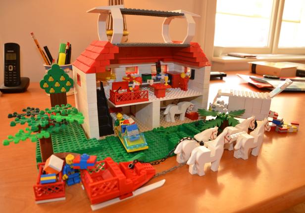 Ein zweistöckiges Lego-Haus mit Pferdeschlitten und Figuren.
