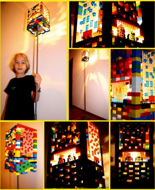 Ein Junge steht neben einer Stehlampe mit einem Lampenschirm aus bunten Legosteinen.