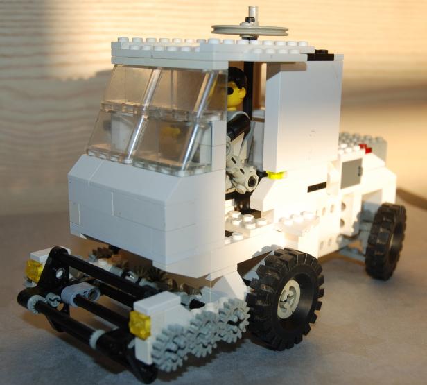 Ein weißes Lego-Fahrzeug mit einer gelben Minifigur am Steuer.