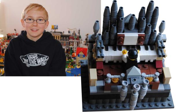 Ein Junge mit Brille vor einer LEGO-Stadt und einer LEGO-Orgel.