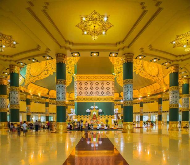 Innenansicht eines reich verzierten Tempels mit goldenen Säulen und Decken in Myanmar.