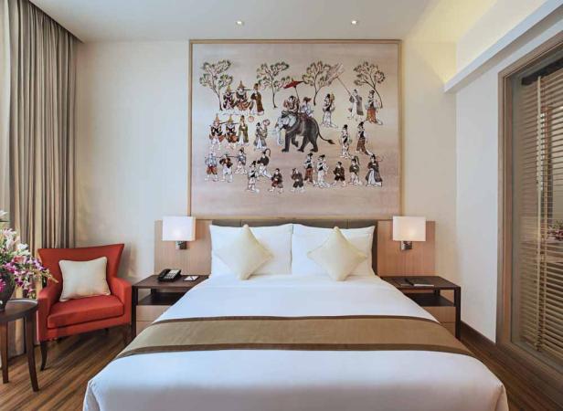 Ein Hotelzimmer mit einem großen Gemälde einer Prozession über dem Bett.