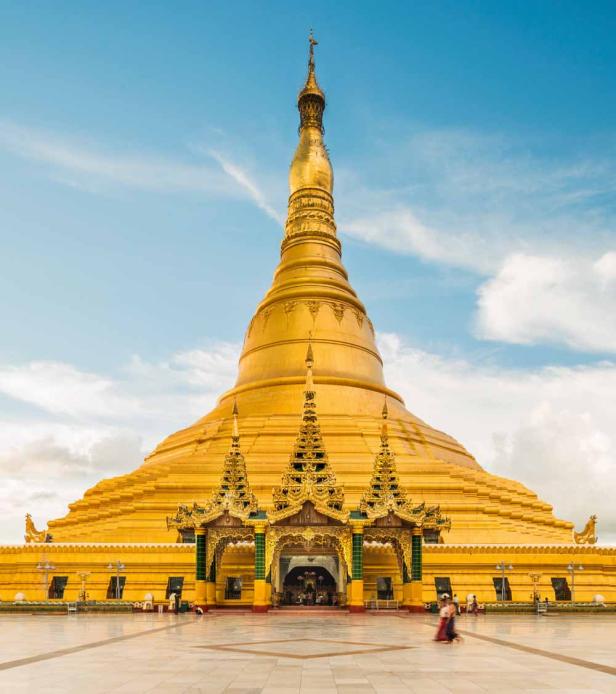 Die strahlend goldene Shwedagon-Pagode in Yangon, Myanmar, erstreckt sich unter einem hellblauen Himmel.