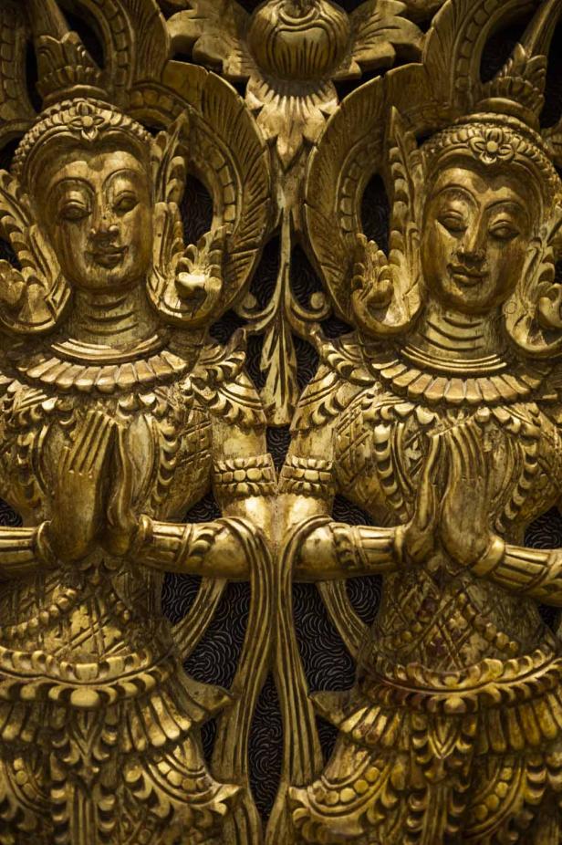 Detailaufnahme einer goldenen Holzskulptur mit zwei weiblichen Figuren.