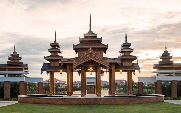 Ein kunstvolles, hölzernes Tor mit traditionellen Verzierungen und Beleuchtung bei Dämmerung.