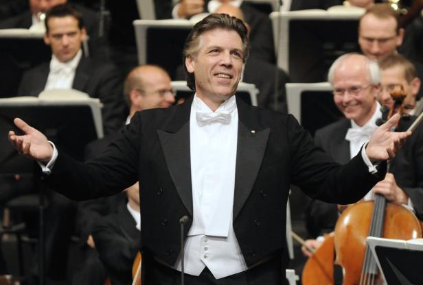 Ein Dirigent leitet ein Orchester mit einem Lächeln.