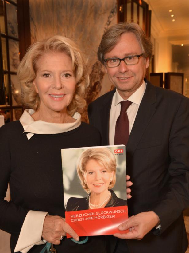 Christiane Hörbiger und ein Mann halten eine Broschüre mit ihrem Porträt und Glückwünschen.