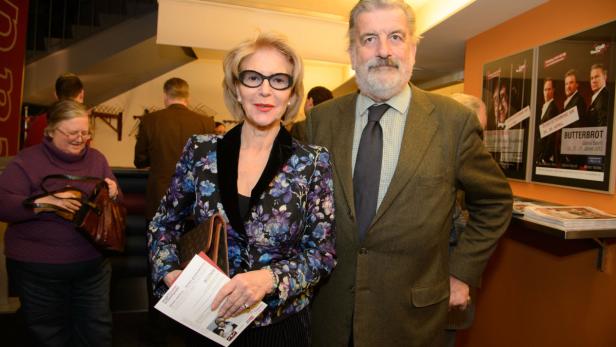 Eine elegante Frau mit Brille und ein Mann im Anzug posieren für ein Foto.