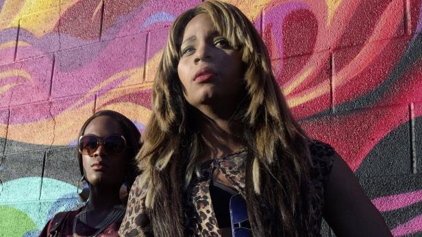 Zwei Frauen posieren vor einer Wand mit Graffiti.