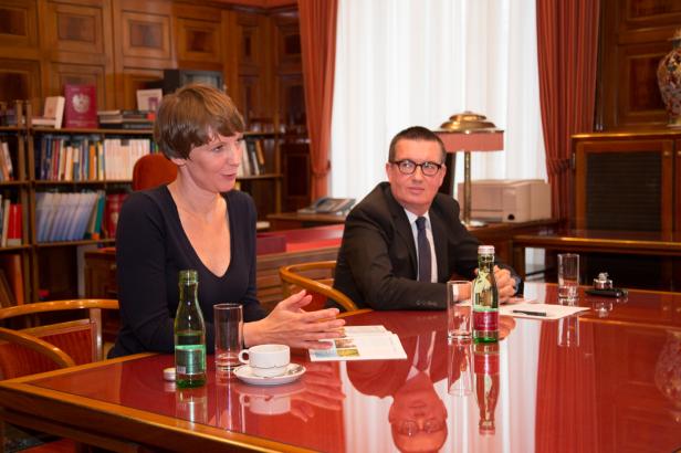 Eine Frau und ein Mann sitzen an einem Tisch in einem Büro und unterhalten sich.