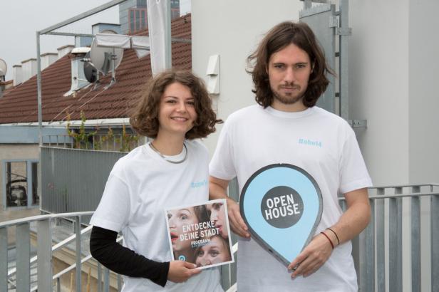 Zwei Personen bewerben das „Open House“-Programm mit Flyern und Schildern.