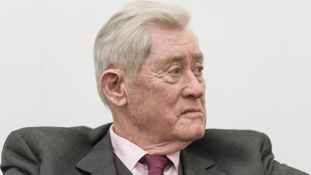 Porträt eines älteren Mannes in Anzug und Krawatte.