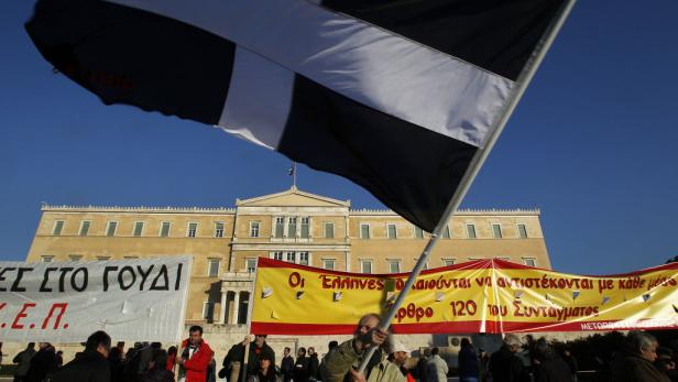 Griechisches Parlament: Protest am Abend vor der Hilfspaket-Entscheidung. Eine Demonstration vor dem griechischen Parlament in Athen mit Transparenten und einer schwarz-weißen Flagge.