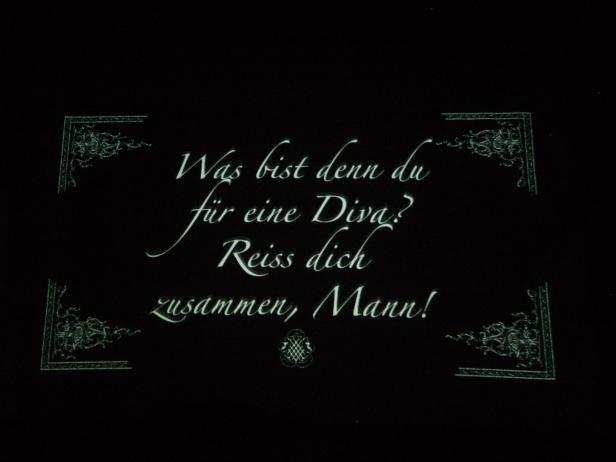 Der Text „Was bist denn du für eine Diva? Reiss dich zusammen, Mann!“ ist auf einer schwarzen Tafel zu lesen.
