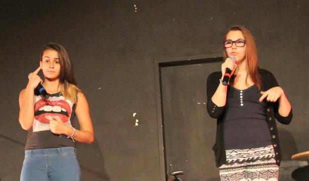 Zwei junge Frauen stehen auf einer Bühne und singen in Mikrofone.