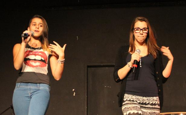 Zwei junge Frauen stehen auf einer Bühne und singen in Mikrofone.