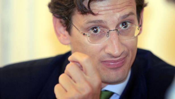 Ein Mann mit Brille und Anzug blickt in die Kamera.