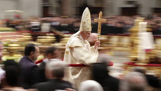 Papst Benedikt XVI. trägt ein goldenes Kreuz durch eine Menschenmenge.
