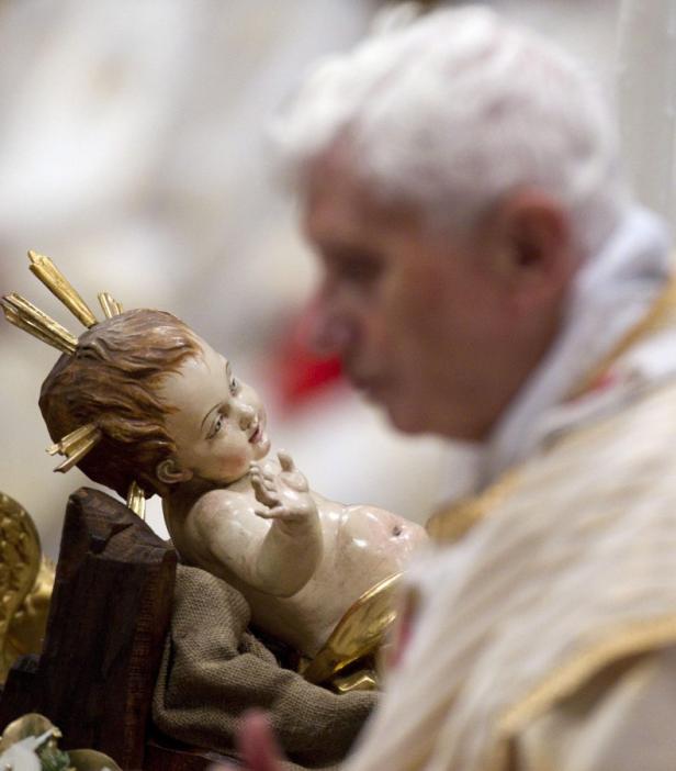 Papst Benedikt XVI. betrachtet eine Jesuskind-Figur.