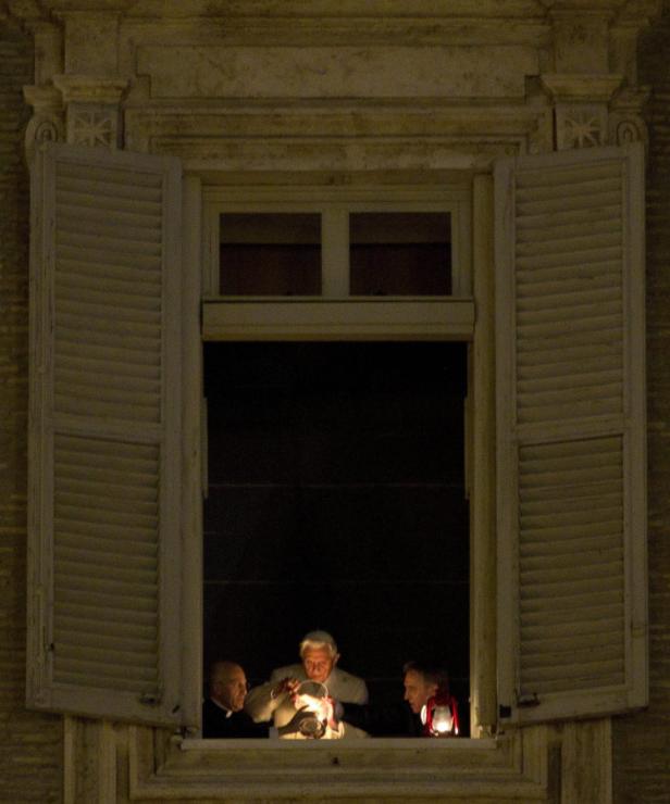 Drei Männer stehen nachts an einem Fenster und halten eine Laterne.