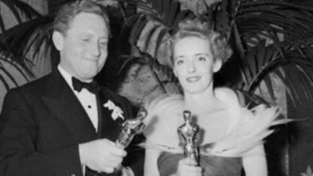 Bette Davis und William Wyler halten ihre Oscars in einer Schwarzweißaufnahme.