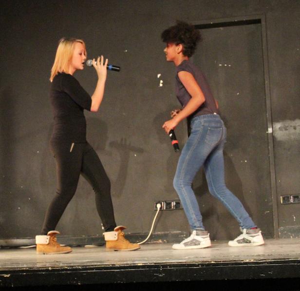 Zwei Sängerinnen stehen mit Mikrofonen auf einer Bühne.