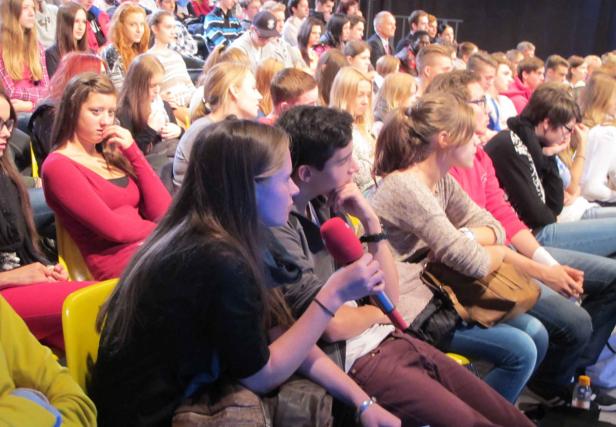 Ein Publikum sitzt während einer Veranstaltung in einem Saal.