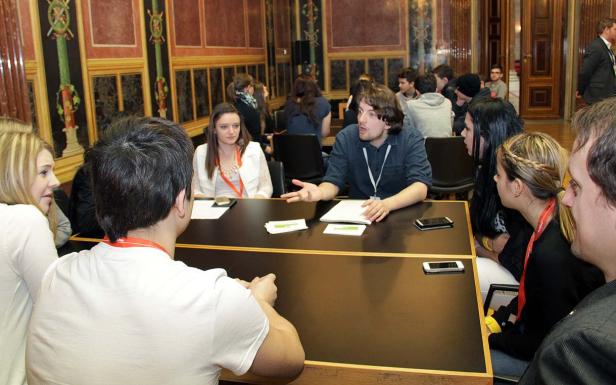 Eine Gruppe junger Leute sitzt an einem Tisch und diskutiert.