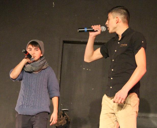 Zwei junge Männer stehen auf einer Bühne und singen in Mikrofone.