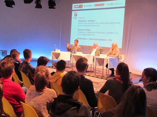 Publikum hört einem Podium mit Daniela G. Camhy, Manfred Rühl und Alois Schörghuber zu.