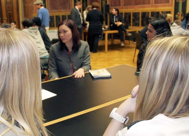 Mehrere Personen sitzen an Tischen in einem Raum, möglicherweise bei einer Veranstaltung.