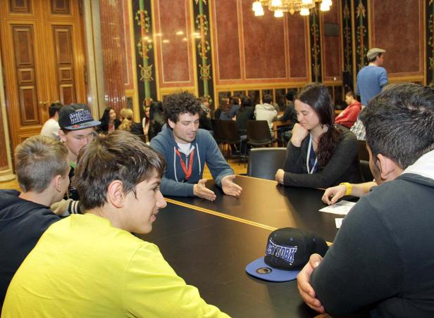 Eine Gruppe junger Leute sitzt an einem Tisch in einem eleganten Raum.