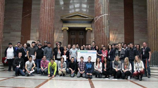 Eine Gruppe junger Menschen posiert mit einem Schild für einen „Ideenkatalog für eine faire Arbeitswelt“.