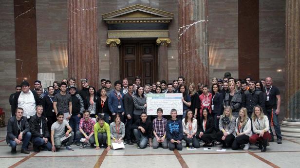 Eine Gruppe junger Menschen posiert mit einem Schild mit der Aufschrift „Ideenkatalog für eine faire Arbeitswelt“.