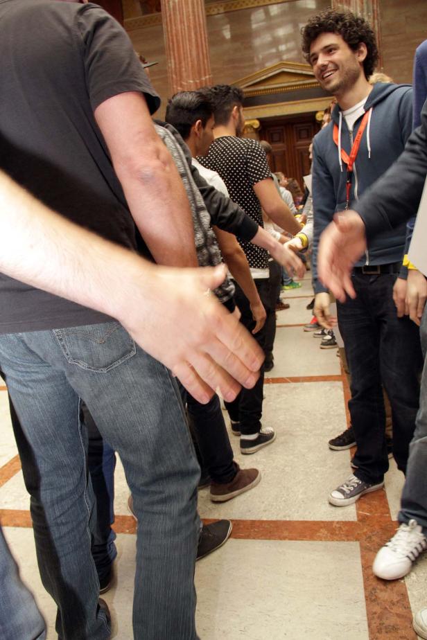 Eine Gruppe von Menschen schüttelt sich die Hände in einem Innenraum.