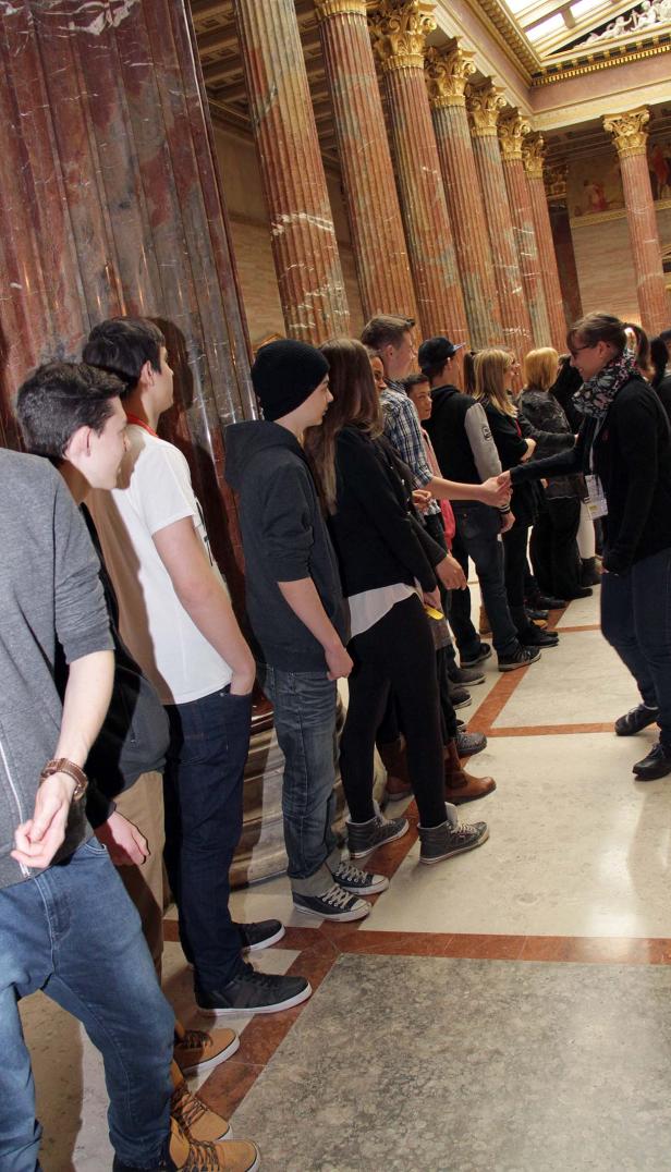 Eine Gruppe von Menschen steht in einer Reihe vor Säulen und schüttelt Hände.