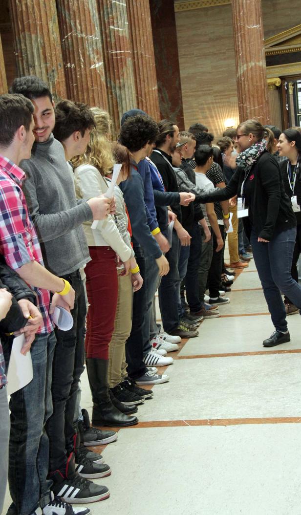 Eine lange Schlange von Menschen steht in einem Gebäude an, um sich die Hände zu geben.