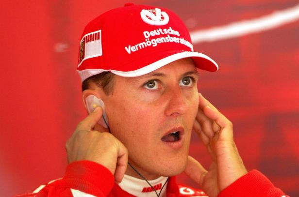 Michael Schumacher mit Kopfhörern und roter Kappe mit Sponsorenlogo.