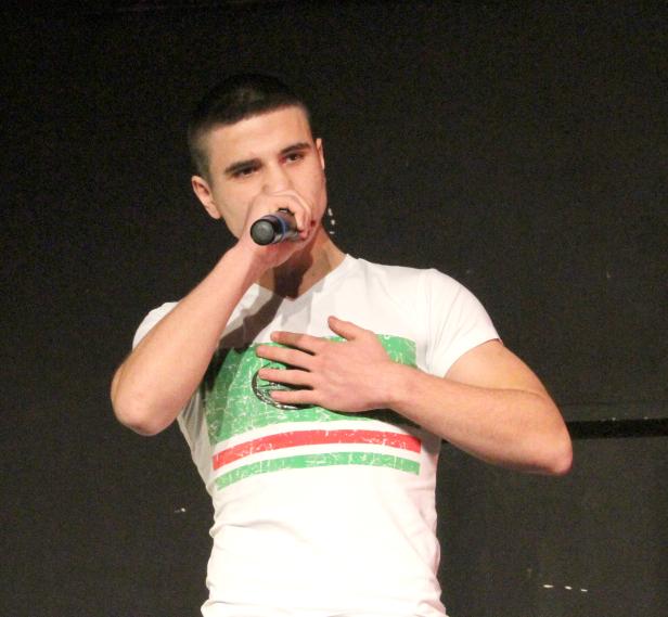 Ein junger Mann singt mit einem Mikrofon in der Hand.