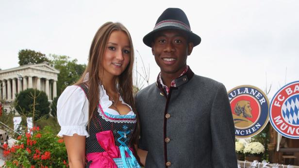 Ein Mann und eine Frau in Tracht vor der Bavaria-Statue in München.
