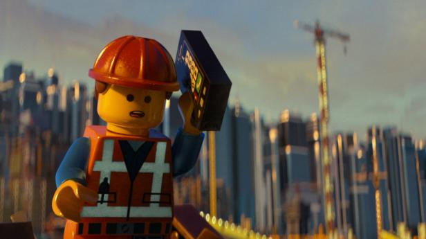 Eine Lego-Figur in Bauarbeiterkleidung hält ein Gerät vor einer Stadtkulisse.