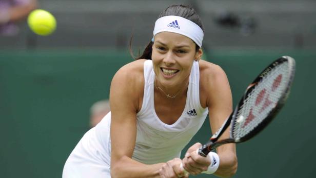 Eine Tennisspielerin mit einem Adidas-Stirnband schlägt einen Ball.